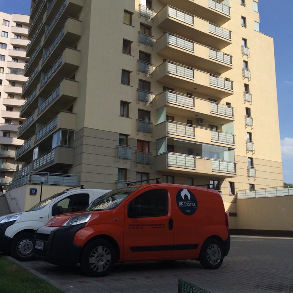 Samochody serwisowe BK INSTAL przy budynku mieszkalnym